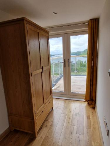 a room with a wooden cabinet and a large window at Luxury Cottage by Fairy Pools 4 in Carbost
