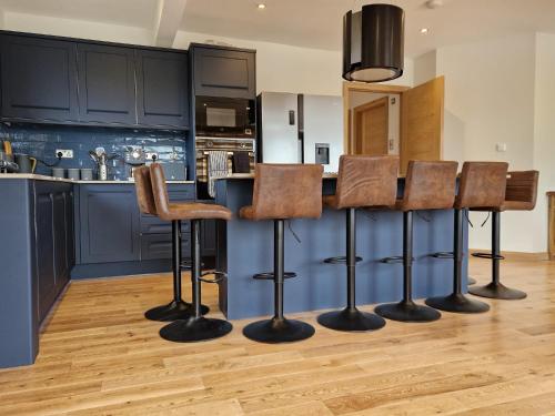 a kitchen with black cabinets and bar stools at Luxury Cottage by Fairy Pools 4 in Carbost