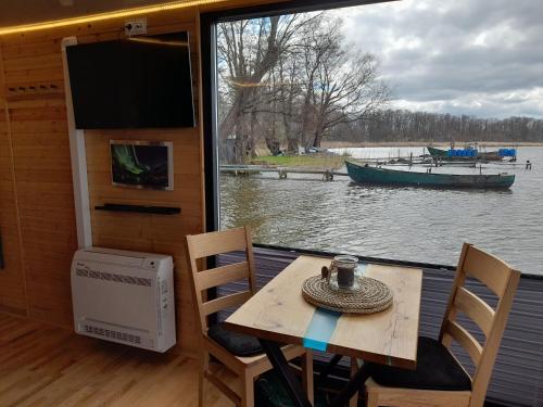 a table and chairs with a view of a boat at Hausboot Am See Robert Döring in Riether Stiege