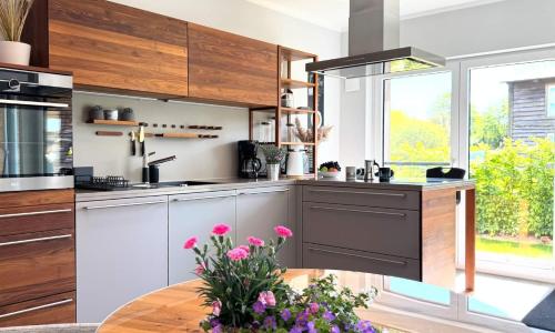 a kitchen with wooden cabinets and a table with flowers at Lütt Kirr in Zingst