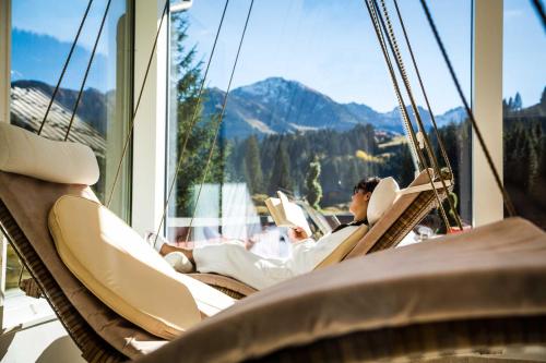 a man is sitting in a porch swing at Alpenhotel DAS KÜREN in Hirschegg