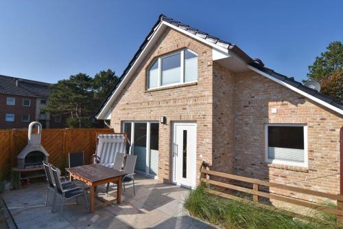 une maison en briques avec une table et des chaises sur un patio dans l'établissement Lokkich Hüs, à Westerland