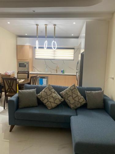 a living room with a blue couch and a kitchen at Allman luxurious one bedroom near beaches in Llandovery