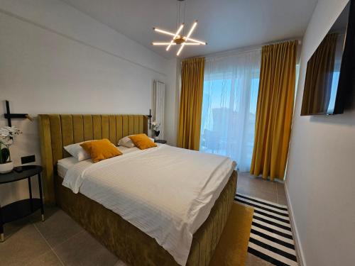 ein Schlafzimmer mit einem Bett mit orangefarbenen Kissen und einem Fenster in der Unterkunft Alezzi Odyssey Mamaia Nord II - Parcare Inclusa in Mamaia Nord – Năvodari