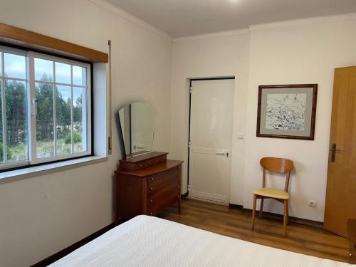 a bedroom with a bed and a mirror and a chair at Casa da Foz do arelho in Nadadouro