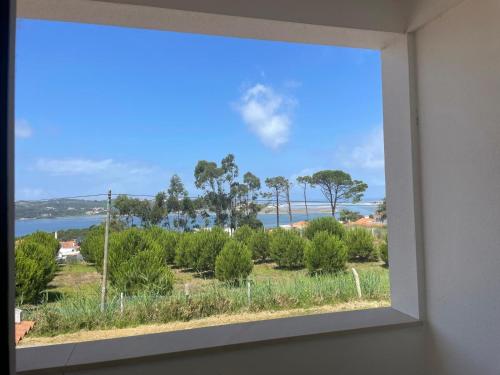 a window with a view of the water and trees at Casa da Foz do arelho in Nadadouro