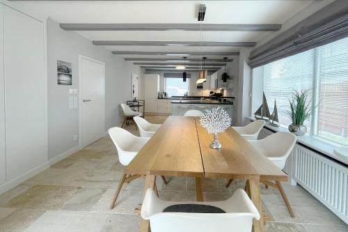 une salle à manger avec une table en bois et des chaises blanches dans l'établissement Ferienwohnung Goede Tiid, à Tinnum