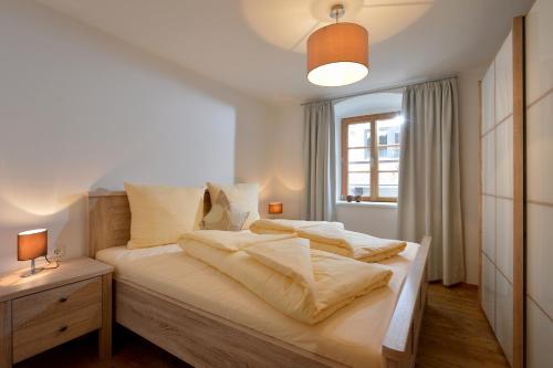 een slaapkamer met een bed met witte lakens en een raam bij Jaegerhaus Appartements in Hopfgarten im Brixental