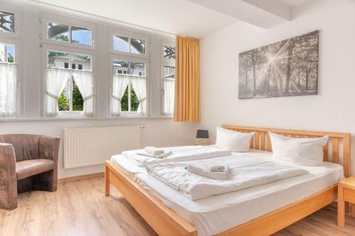 a bedroom with a bed and a chair and windows at Ferienwohnung 11 Villa Eden in Binz