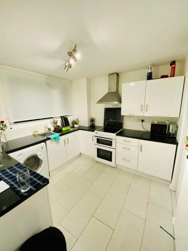 a kitchen with white cabinets and a white tile floor at Bright Double Room near Lewisham Station in London