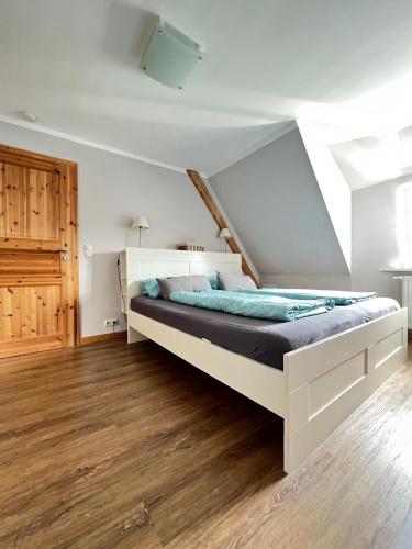 a white bed in a room with a wooden floor at Strandperle in List