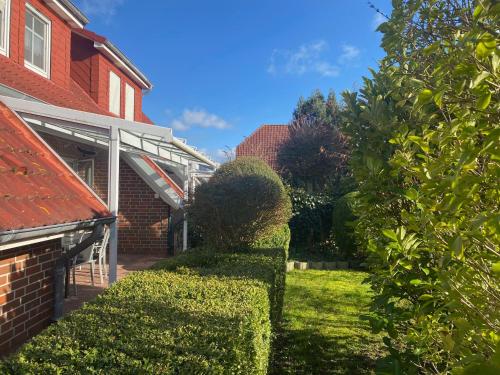 un giardino con cespugli e una casa in mattoni di Sylke a Carolinensiel