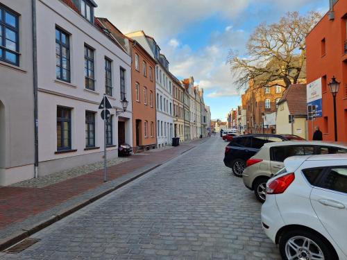 a cobblestone street with parked cars and buildings at Walfisch im Zentrum - ABC350 in Wismar