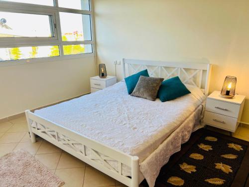 a bedroom with a white bed with blue pillows at Appartement Bouznika Bay Golf Beach in Bouznika