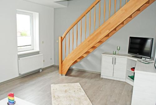 a living room with a staircase and a television at Ferienwohnungen Udars auf Rügen in Udars
