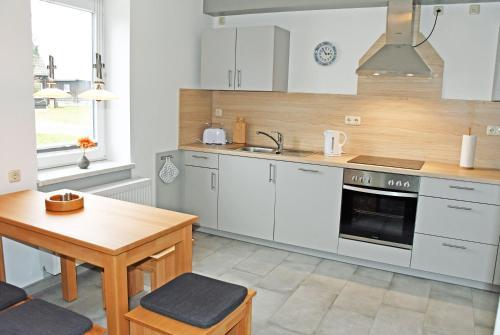 a kitchen with white cabinets and a wooden table at Ferienwohnungen Udars auf Rügen in Udars