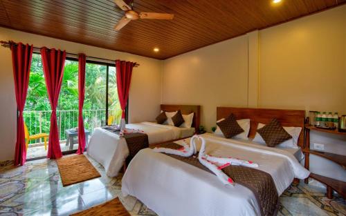 a bedroom with two beds and a window at La Roca Inn in Assagao