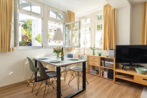 a dining room with a table and chairs and windows at Ferienwohnung 14 Villa Eden in Binz