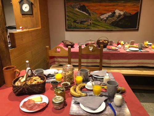 a table with a red table cloth with food on it at Chez Mamie Anna (B&B et Chalet) in Bessans