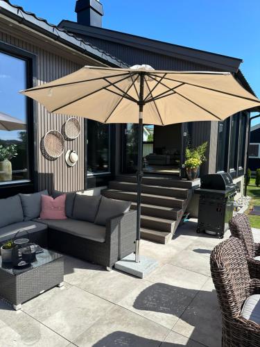 a patio with a couch and an umbrella at Enebolig på Nesbrygga 