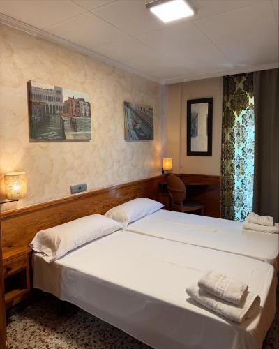 a bedroom with a bed with two towels on it at HOSTAL GALICIA CARDEDEU in Cardedeu