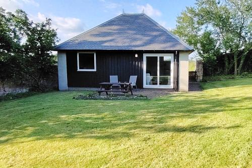a small house with a picnic table in a yard at Orchard Cottages at Gorton House in Roslin