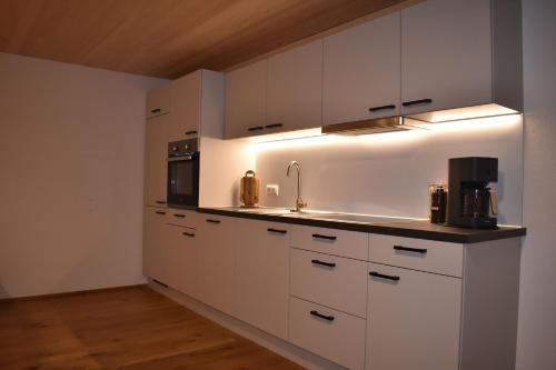 a kitchen with white cabinets and a sink at Ferienwohnung BergTraum in Schoppernau