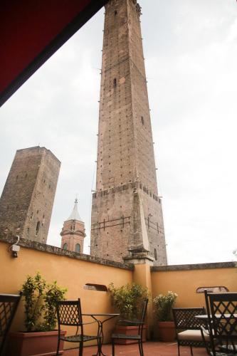 a large tower with chairs and tables in front of a building at Albergo Garisenda con terrazza panoramica sulle Due Torri in Bologna