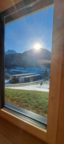 a window with a view of a building and the sun at Ferienwohnung BergTraum in Schoppernau
