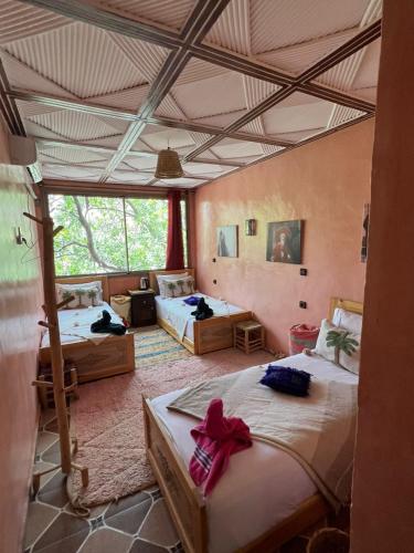 a bedroom with two beds and a large window at Riad Atlas Garden in Imlil