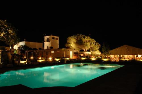 a swimming pool at night with a building in the background at Masseria Luco in Martina Franca