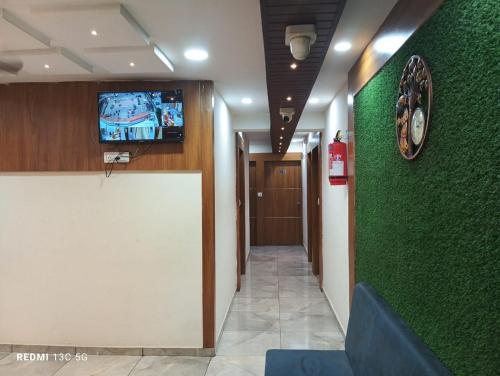 Un pasillo con una pared verde con un televisor encima. en Hotel Shera inn, en Ahmedabad