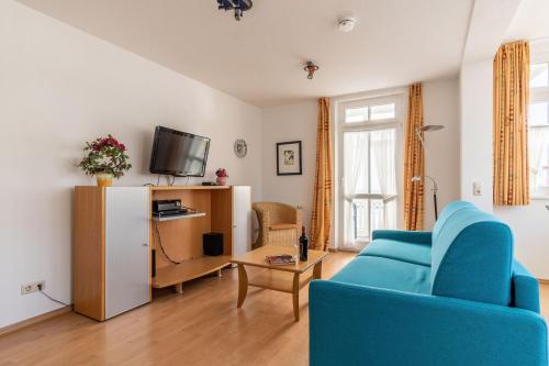 a living room with a blue couch and a tv at Ferienwohnung 17 Villa Eden in Binz