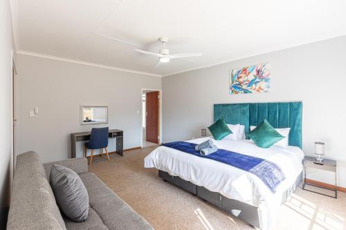 a bedroom with a large bed and a couch at Forest View Cottage in Muldersdrift