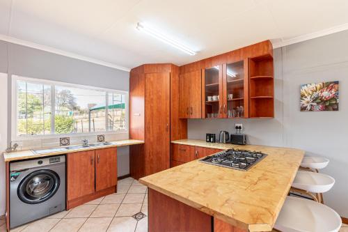 a kitchen with wooden cabinets and a washer and dryer at Forest View Cottage in Muldersdrift