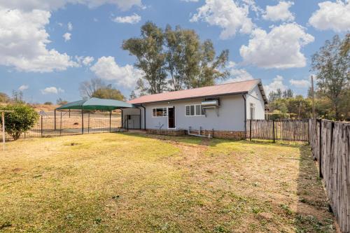 a white house with a fence and a yard at Forest View Cottage in Muldersdrift