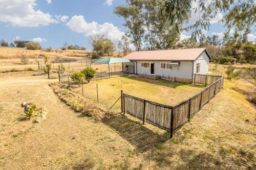 a house in a field with a fence at Forest View Cottage in Muldersdrift