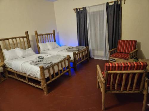 カラトゥにあるAfrican Royal Villa and Campsiteのベッド2台と椅子2脚が備わる客室です。