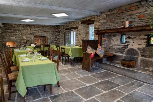 a restaurant with green tables and chairs and a stone wall at Country House La Villa in Villadossola