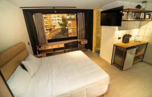 a bedroom with a large white bed and a window at NUIT Bogota in Bogotá
