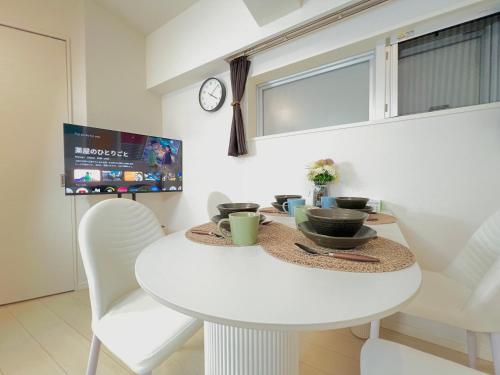 a white dining room table with white chairs and a clock at Shinjuku City Apt, 2DB , Free WiFi in Tokyo