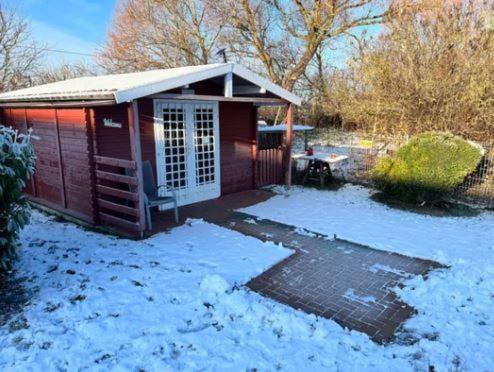 a smallshed with snow on the ground in a yard at Ferienwohnungen Rügen mit Hund in Granskevitz