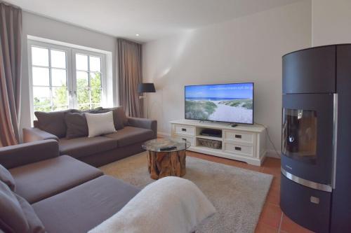 a living room with a couch and a flat screen tv at Ferienhaus Helen in Morsum