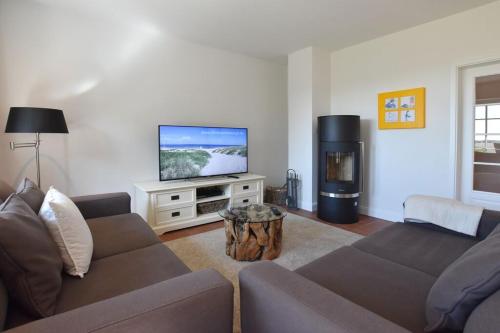 a living room with a couch and a flat screen tv at Ferienhaus Helen in Morsum