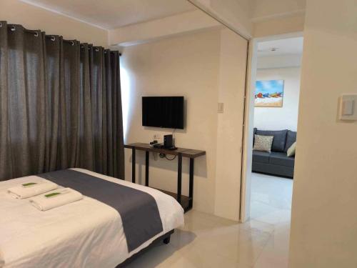 a bedroom with a bed and a tv and a couch at Persimmons Mabolo, Cebu City in Cebu City