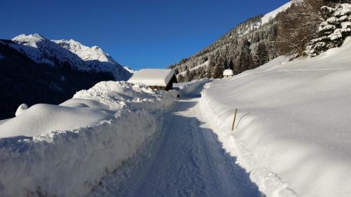 a road covered in snow next to a mountain at Bergfee Natur Appartements in Nesselwängle