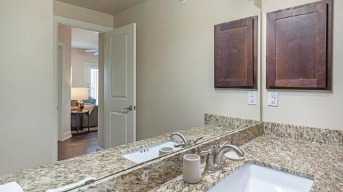 Un baño con lavabo y un espejo grande. en Landing at Mission Hill - New Braunfels, en New Braunfels