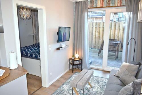 een woonkamer met een bank en een tv aan de muur bij Lütt Hus an de See Ferienwohnung in Niendorf