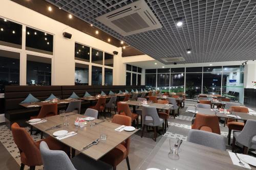 a restaurant with wooden tables and chairs and windows at Amerin Hotel Johor Bahru in Johor Bahru