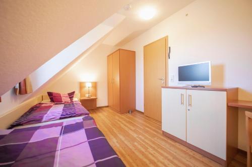 a attic room with a bed and a tv at Ferienhäuser Greetsiel - Urlaub mit Haustier in Ostfriesland in Greetsiel